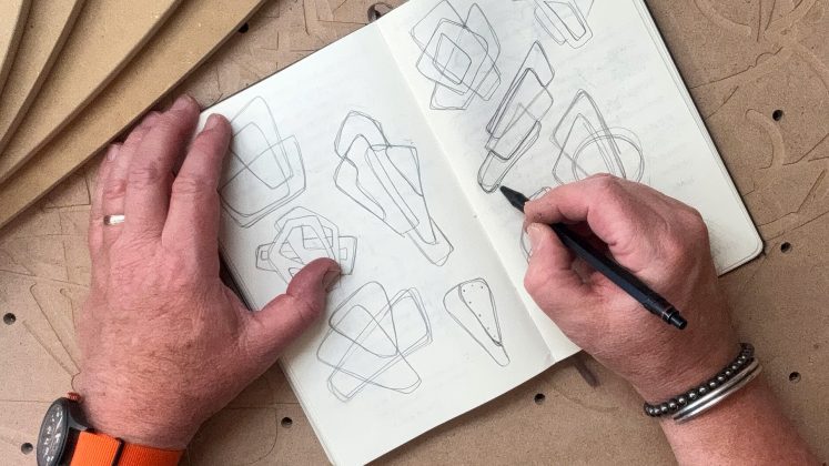 hands holding a pen and drawing in a notebook