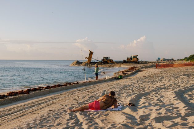 people laying on a beach with construction equipment in the background